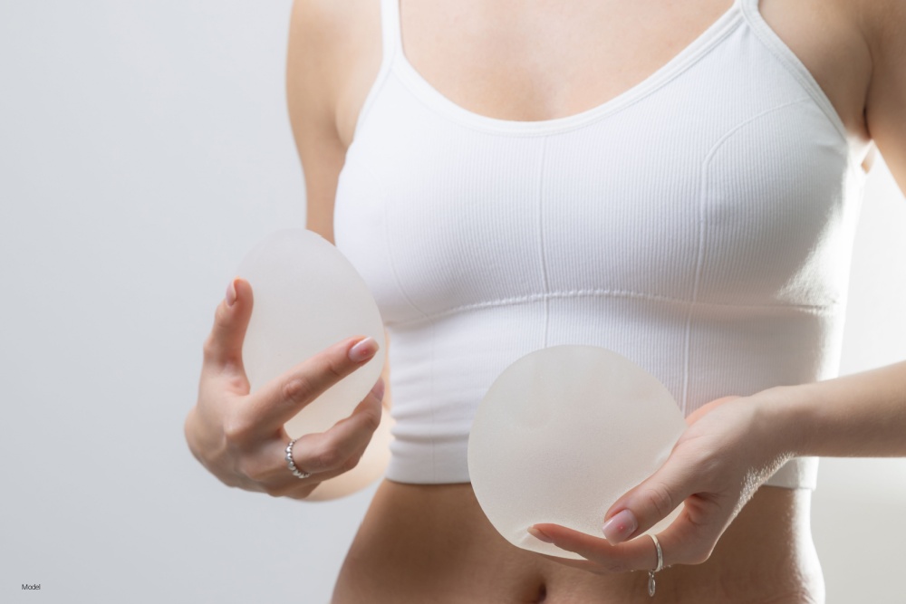 Woman holding and comparing breast implants