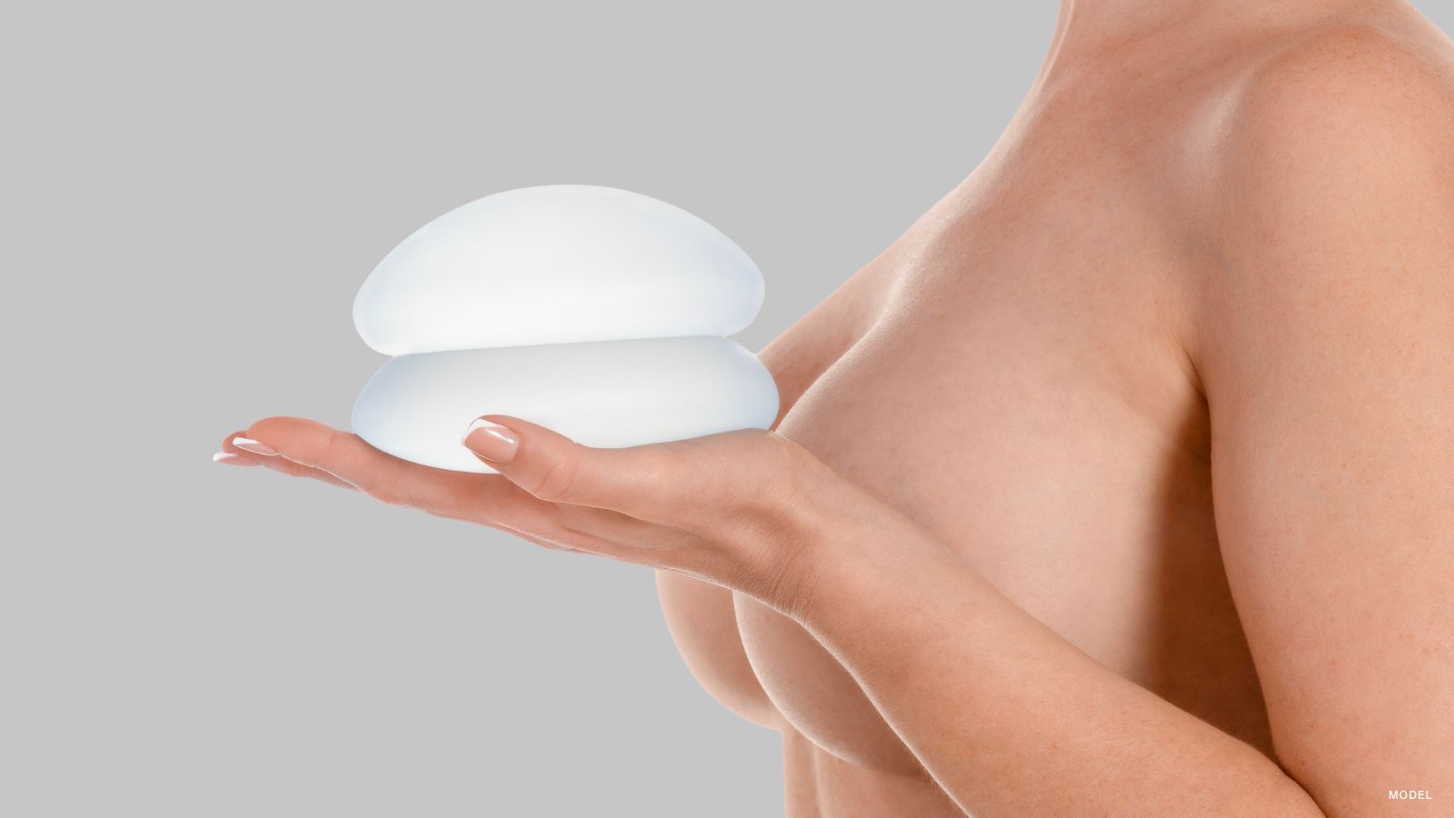 Woman holding breast implants close to her chest