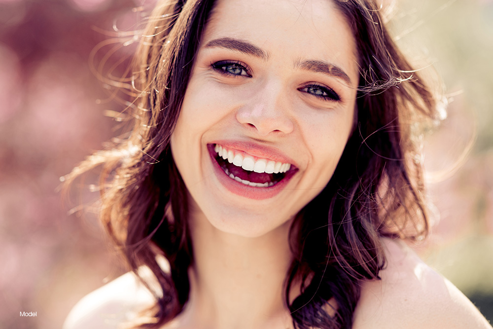 Young woman with dark hair smiling outdoors